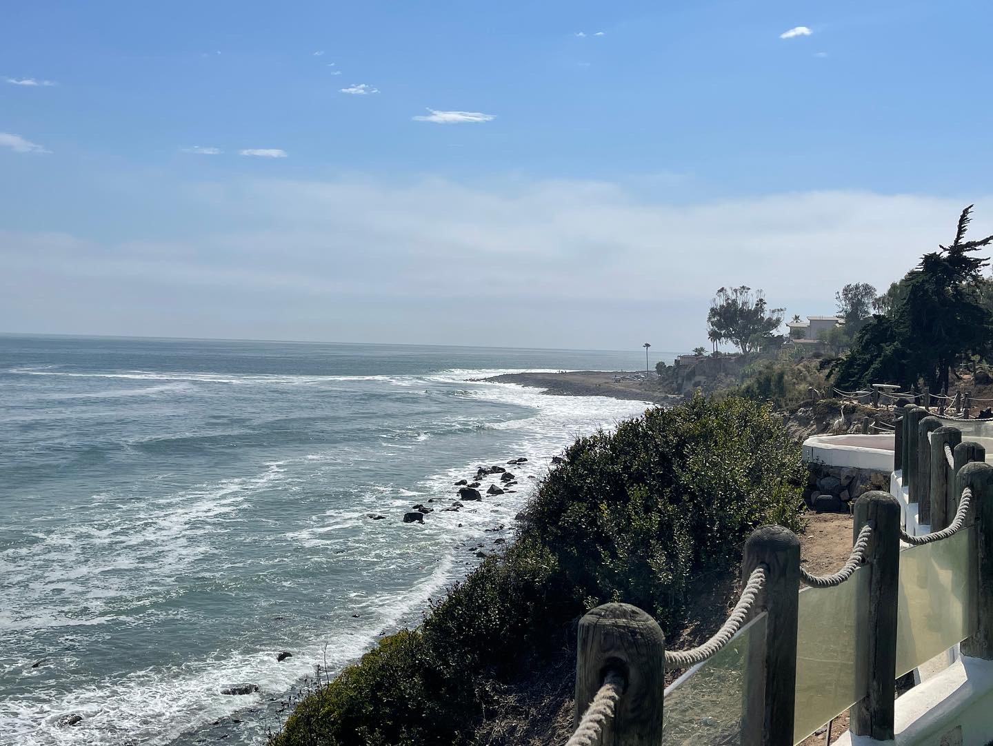 Ocean waves along the rocky Ensenada coastline beside a seaside walkway